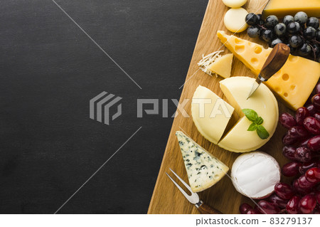 flat lay mix of gourmet cheese and grapes on cutting board with copy space. High quality and resolution beautiful photo concept flat lay mix of gourmet cheese and grapes on cutting board with copy space. High quality and resolution beautiful photo concept 83279137