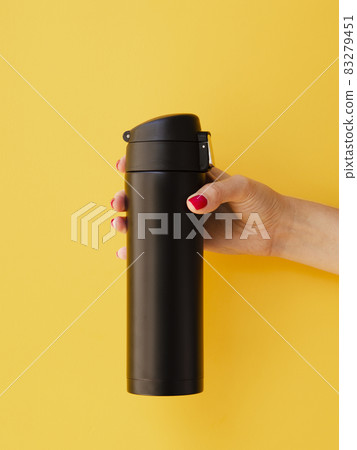 hand holding thermos mock up yellow background. High quality and resolution beautiful photo concept hand holding thermos mock up yellow background. High quality and resolution beautiful photo concept 83279451
