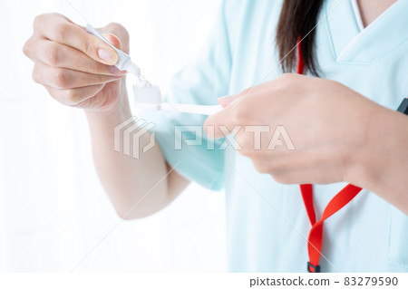 Female dental hygienist who puts toothpaste on a toothbrush [Parts cut] 83279590