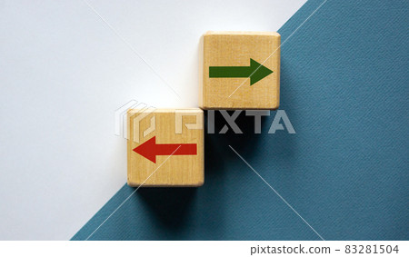 Conceptual image of choice and direction. Wooden cubes with arrows pointing in opposite directions. Beautiful white and blue background, copy space. 83281504