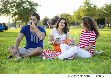 Three friends sitting on the grass in the park Three friends sitting on the grass in the park 83281705