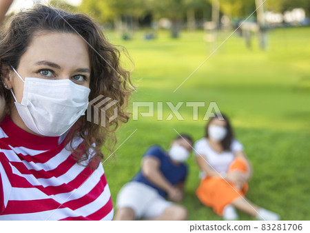 Three friends sitting on the grass and taking a selfie Three friends sitting on the grass and taking a selfie 83281706