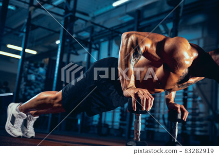 Portrait of muscled athlete, bodybuilder workouts alone at sport gym, indoors. Concept of sport, activity, healthy lifestyle 83282919