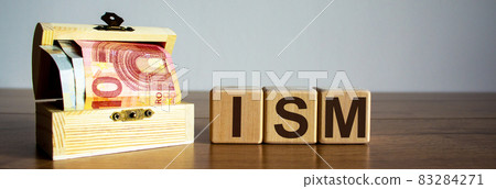 Concept word ISM on cubes on a beautiful wooden table, small chest with euro bills. Concept word ISM on cubes on a beautiful wooden table, small chest with euro bills. 83284271