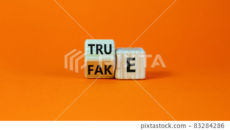 Fake or true symbol. Turned a wooden cube and changed the word 'fake' to 'true' or vice versa. Beautiful orange table, orange background, copy space. Business and fake or true concept. Fake or true symbol. Turned a wooden cube and changed the word 'fake' to 'true' or vice versa. Beautiful orange table, orange background, copy space. Business and fake or true concept. 83284286
