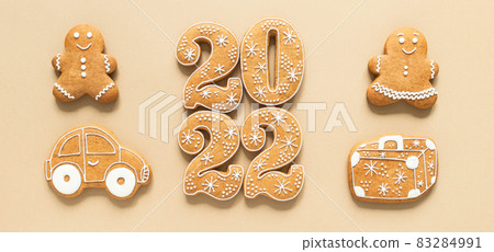 Gingerbread cookies in the form of numbers, Happy New Year 2022, gingerbread man and woman, suitcase and car on beige background. Travel concept Top view. Flat lay Gingerbread cookies in the form of numbers, Happy New Year 2022, gingerbread man and woman, suitcase and car on beige background. Travel concept Top view. Flat lay 83284991