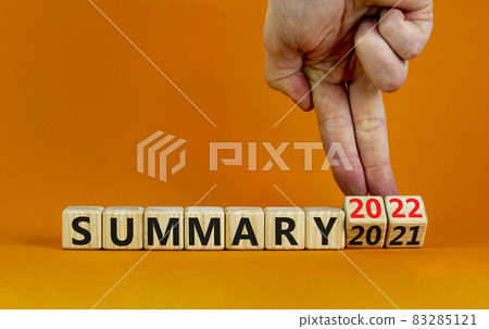 Symbol of planning 2022 summary new year. Businessman turns a wooden cube and changes words 'summary 2021' to 'summary 2022'. Beautiful orange background, copy space. Business, 2022 summary concept. Symbol of planning 2022 summary new year. Businessman turns a wooden cube and changes words 'summary 2021' to 'summary 2022'. Beautiful orange background, copy space. Business, 2022 summary concept. 83285121