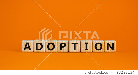 Wooden cubes with the inscription 'adoption'. Beautiful orange background, copy space. 83285134