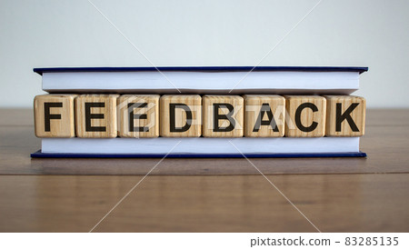 Concept word 'feedback' on wooden cubes between pages of a book on a beautiful wooden table. White background. Business concept. 83285135