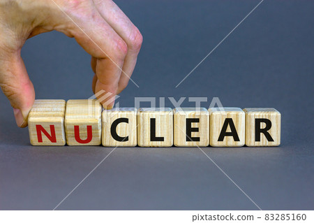 Nuclear or clear symbol. Businessman turns a cube and changes the word 'nuclear' to 'clear'. Beautiful grey background. Nuclear or clear and business concept. Copy space. 83285160