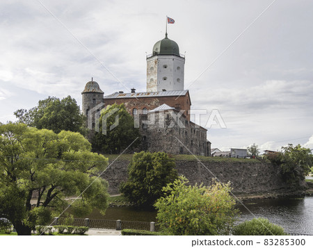 Medieval Vyborg Castle is Swedish-built fortress. White tower of Saint Olav with flag. Historical and architectural landmark. 83285300