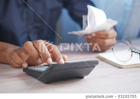 Close up of man hand using calculator and holding bills Close up of man hand using calculator and holding bills 83285705