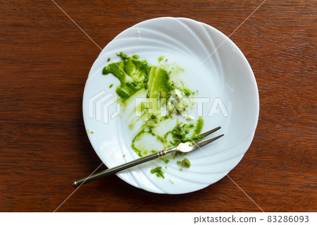 Empty dirty dish after green tea cake and dessert fork. Empty dirty dish after green tea cake and dessert fork. 83286093
