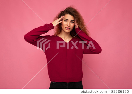 Portrait of young emotional beautiful brunette curly woman with sincere emotions wearing trendy pink Portrait of young emotional beautiful brunette curly woman with sincere emotions wearing trendy pink 83286130