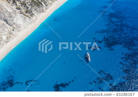 Lefkada, Greece. Remote white Egremni beach with lonely luxury yacht boat on the turquoise colored bay on Ionian Sea Lefkada, Greece. Remote white Egremni beach with lonely luxury yacht boat on the turquoise colored bay on Ionian Sea 83286167