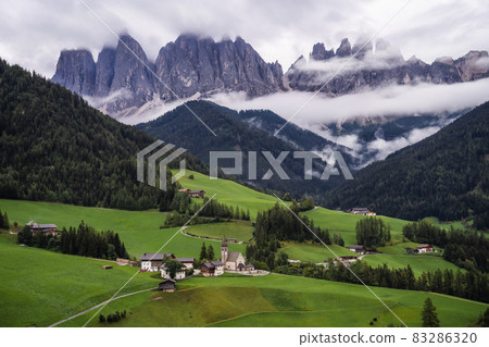 St Magdalena church in Val di Funes valley, Dolomites, Italy. Furchetta and Sass Rigais mountain peaks in background 83286320