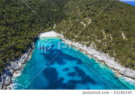 Aerial top down view of Dafnoudi beach in Kefalonia, Greece. Remote bay with pure crystal clean turquoise sea water surrounded by cypress trees 83286340
