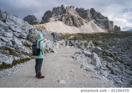 Woman with backpack hiking in Tre Cime National park. Dolomites, Italy, Europe Woman with backpack hiking in Tre Cime National park. Dolomites, Italy, Europe 83286439