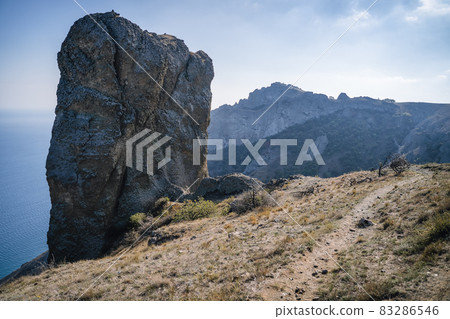 Rock called Devil's finger in the Karadag nature reserve against the blue sky. Black sea. Crimea Rock called Devil's finger in the Karadag nature reserve against the blue sky. Black sea. Crimea 83286546