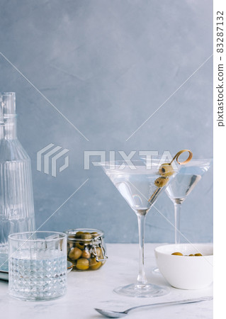 Martini cocktail in a glass on blue background with olives. Martini cocktail in a glass on blue background with olives. 83287132