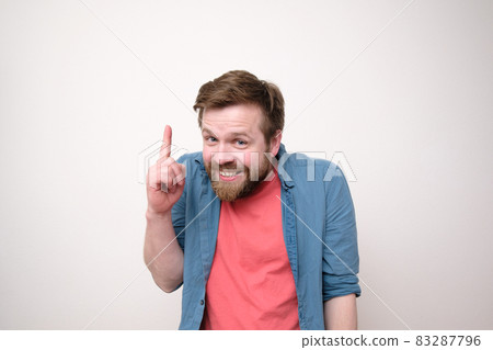 Sly, weird man came up with something, he raised his index finger up and looks insidious. White Sly, weird man came up with something, he raised his index finger up and looks insidious. White 83287796