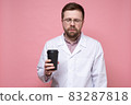 Doctor in a white coat and glasses is very tired and looks sleepy, he holds a paper cup of coffee in 83287818