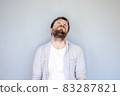Unhappy, tired Caucasian bearded man in a shirt raised head and looked up, hands down in 83287821