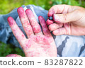 Close-up of a palm painted in purple from blueberry juice, in the forest. Harvesting berries on a 83287822