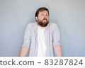 Bewilderment bearded man in a shirt shrugs in surprise and looks at the camera with a strange and 83287824