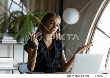 Engaged young business woman in headphones working at laptop Engaged young business woman in headphones working at laptop 83289705