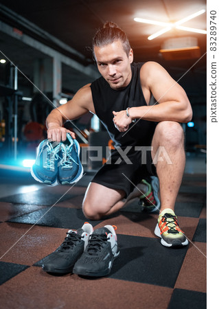 young handsome man choosing shoes for run training in gym 83289740