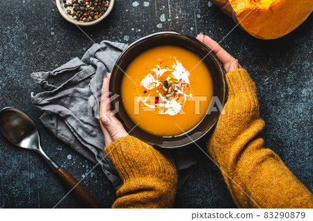 Female hands with bowl of pumpkin soup 83290879