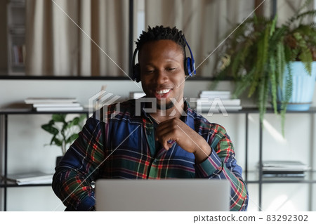 Happy African American hipster student guy in headphones watching webinar Happy African American hipster student guy in headphones watching webinar 83292302