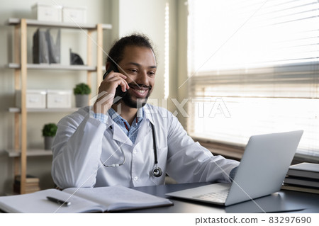 Happy mixed race Black practitioner making telephone call from office 83297690