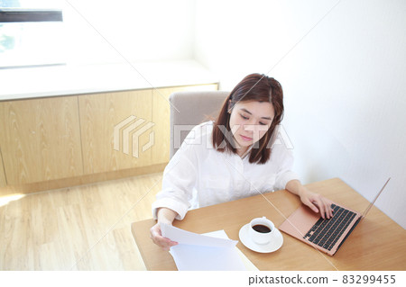 asian woman read the letter and using laptop to caculate  83299455