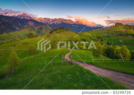 Rural landscape and snowy mountains at sunset, Carpathians, Romania 83299726