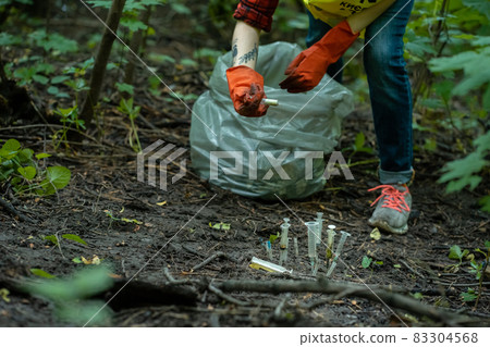 volunteer cleaning up used syringe in park and standing by bunch of garbage bag volunteer cleaning up used syringe in park and standing by bunch of garbage bag 83304568