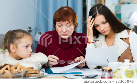 Senior lady with adult family looking worriedly at papers Senior lady with adult family looking worriedly at papers 83305076