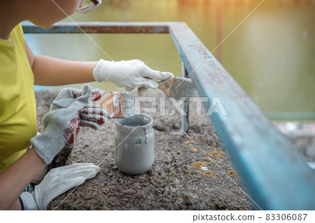 volunteer worker painting with brush or roller and renovate railing or fence volunteer worker painting with brush or roller and renovate railing or fence 83306087