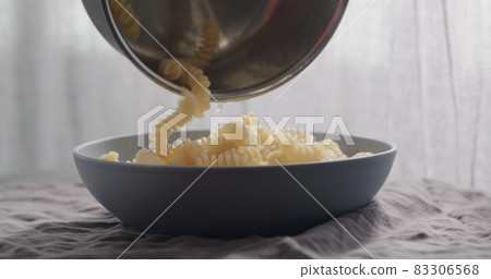 pour freshly cooked fusilli pasta in blue bowl pour freshly cooked fusilli pasta in blue bowl 83306568