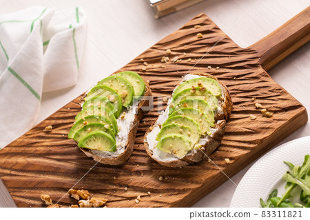 Sliced avocado on toast bread with nuts. Breakfast and healthy food concept. 83311821