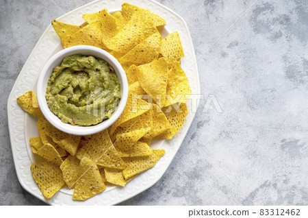 Nachos chips and homemade guacamole, tortilla chips snack. Party food. Top view. Nachos chips and homemade guacamole, tortilla chips snack. Party food. Top view. 83312462
