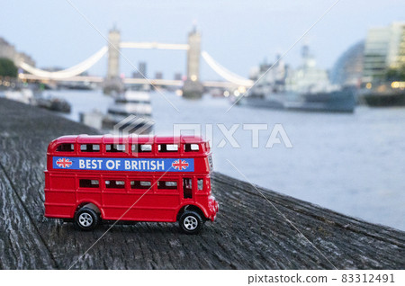 London, U.K., July 22,2021 - Red London Bus miniature london tower bridge on background. London, U.K., July 22,2021 - Red London Bus miniature london tower bridge on background. 83312491