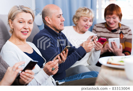 Mature friends are sitting on sofa and chatting on phone Mature friends are sitting on sofa and chatting on phone 83313004