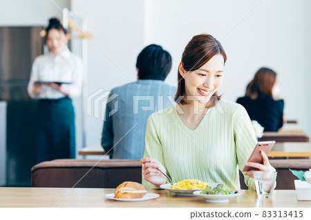 一位年輕女子在咖啡館吃飯時看著她的智能手機 83313415