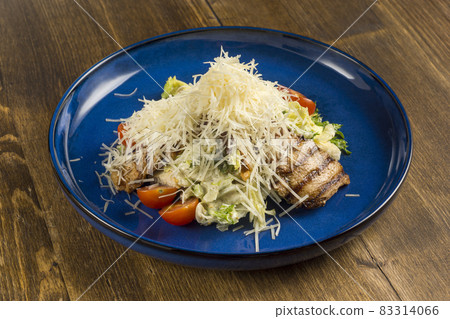 Dish of fried meat with fresh vegetables sprinkled with fresh grated cheese Dish of fried meat with fresh vegetables sprinkled with fresh grated cheese 83314066