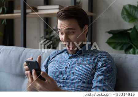 Head shot overjoyed surprised man looking at smartphone screen 83314919
