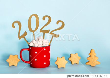 Christmas or New Year 2022 creative concept. Hot chocolate in red mug and golden numbers 2022, copy space 83316155