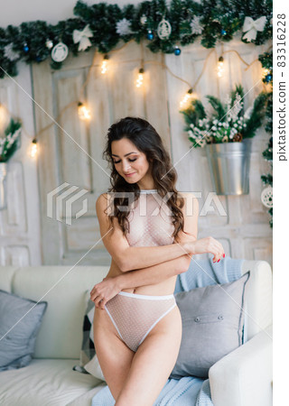 Tall slender girl in sexy lingerie alluring by the fireplace in the Christmas atmosphere. Tall slender girl in sexy lingerie alluring by the fireplace in the Christmas atmosphere. 83316228