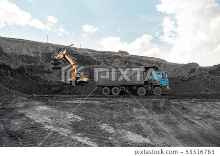 Large quarry dump truck. Loading the rock in dumper. Loading coal into body truck. Production useful minerals. Mining truck mining machinery, to transport coal from open-pit as the Coal Production Large quarry dump truck. Loading the rock in dumper. Loading coal into body truck. Production useful minerals. Mining truck mining machinery, to transport coal from open-pit as the Coal Production 83316763